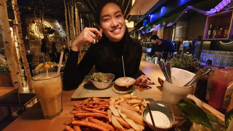 asian woman eating a hamburger and french fries