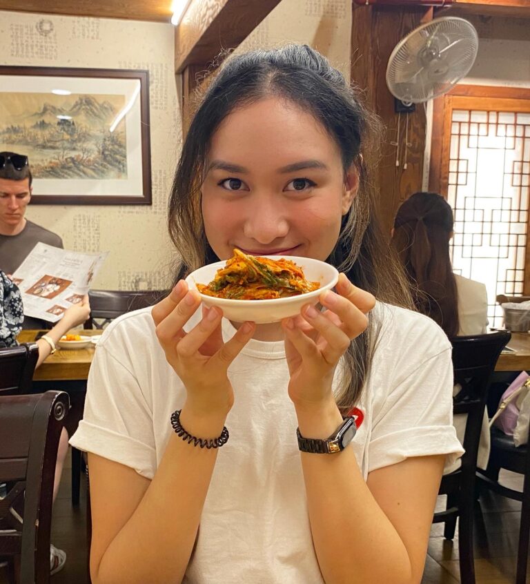 a woman holding kimchi in a restaurant in Seoul, South Korea